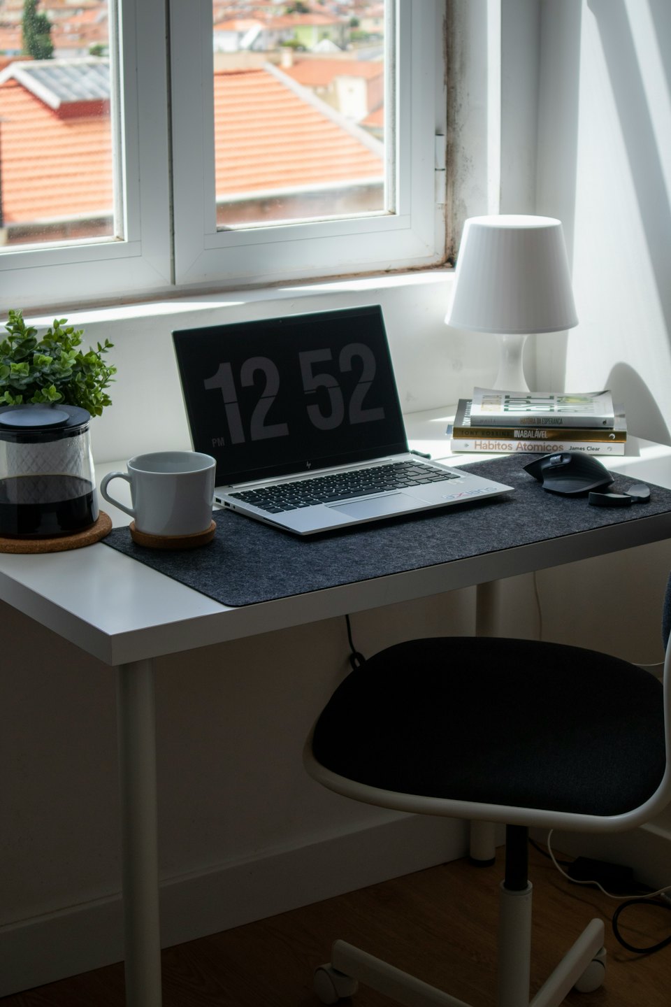 Scrivania moderna per ufficio in casa con laptop, tazza e pianta.