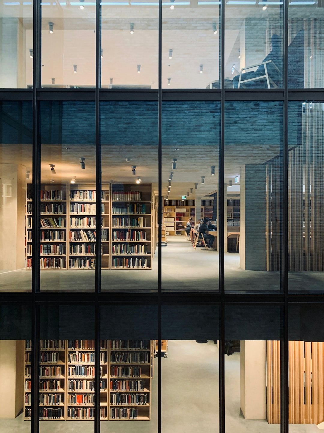 Persone che studiano in una biblioteca moderna e luminosa su più piani.